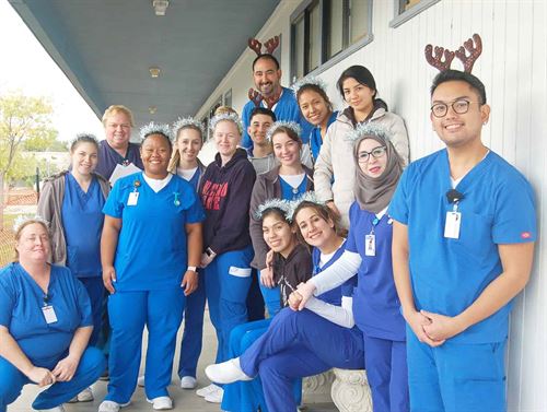 Group of students wearing scrubs all wearing antlers 